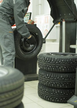 Lastik tamircisiyim. Atölyede arabanın tekerleklerini dengeliyorum..