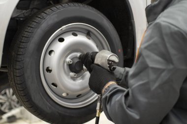 Tire service. Mechanic attaches the wheel to the car
