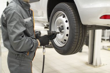Tire service. Mechanic attaches the wheel to the car
