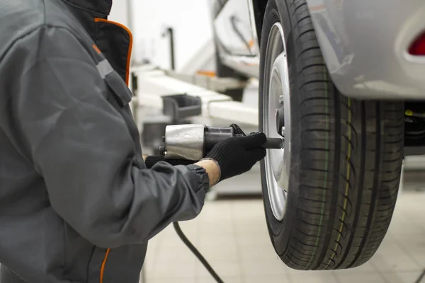 Däckservice. Mekaniker fäster hjulet på bilen — Stockfoto