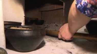 In a pottery workshop, a man takes clay pots out of the oven.