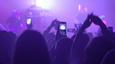 People at the concert shoot videos on their mobile phones.