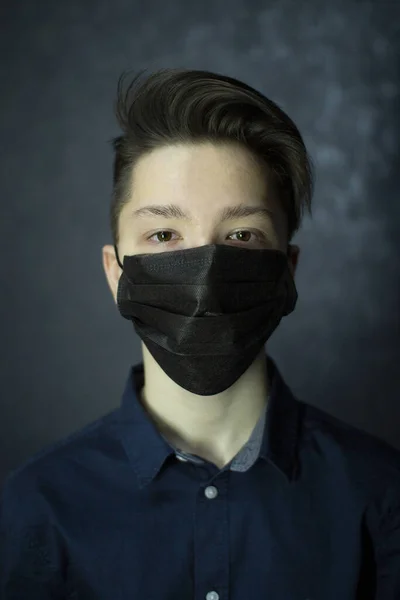 Retrato de un adolescente de ojos marrones con una máscara médica negra. Protección antivirus . — Foto de Stock