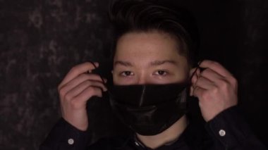 Siyah tıbbi maskeli kahverengi gözlü bir gencin portresi. Antivirüs koruması.