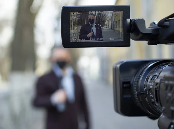 Un periodista europeo de mediana edad con una máscara médica protectora está reportando en una ciudad desierta . —  Fotos de Stock