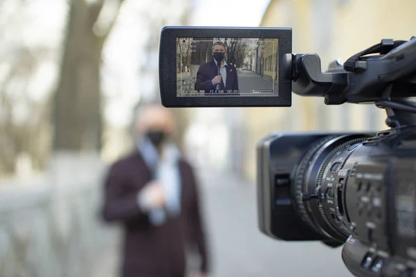 Un periodista europeo de mediana edad con una máscara médica protectora está reportando en una ciudad desierta . — Foto de Stock
