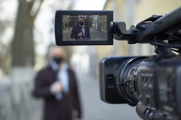 Un periodista europeo de mediana edad con una máscara médica protectora está reportando en una ciudad desierta . — Foto de Stock