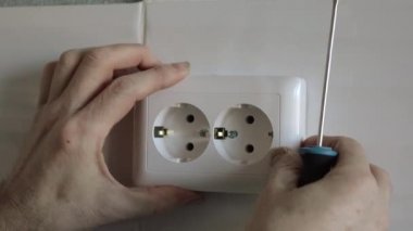 Elektrikçi prizi duvara sabitlemek için tornavida kullanır..