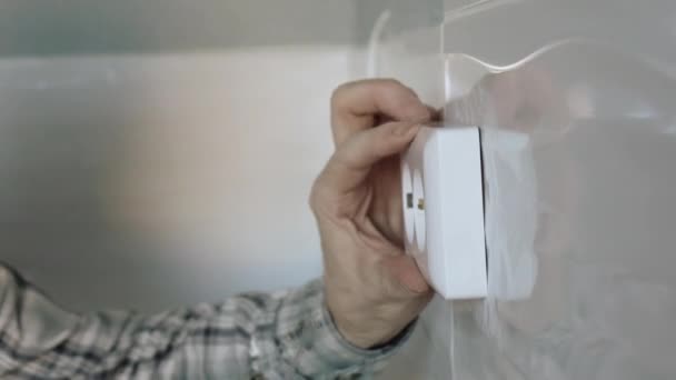 O eletricista usa uma chave de fenda para fixar a tomada à parede . — Vídeo de Stock