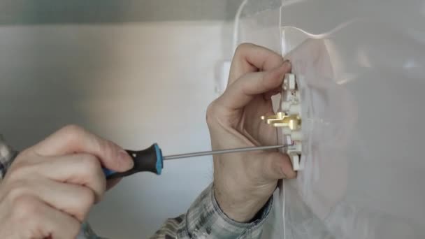 The electrician uses a screwdriver to secure the socket to the wall. — Stock Video