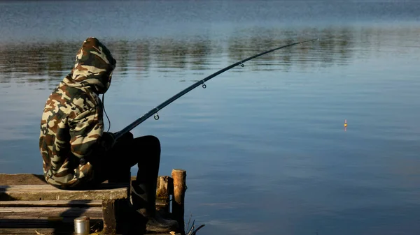 Fiskare i kamouflage vid sjön. Fiske med flytspö på vattnet. — Stockfoto