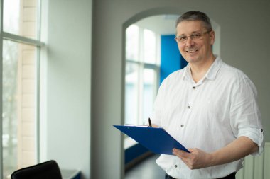 Beyaz gömlekli bir adam not defterine not alır..