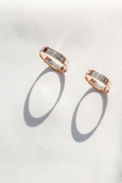 浪漫的结婚戒指背景，有两个金戒指，垂直平衡在明亮的背景上，复制空间用于邀请卡或贺卡 — 图库照片