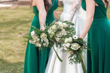 Gelin ve nedime ellerinde çiçek buketleri tutuyor. Gülen gelin ve nedimeler dışarıda ayakta duran komik hikayeler anlatırlar.