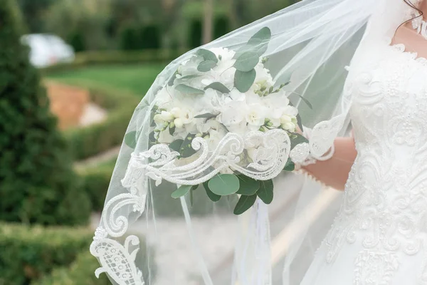Belo buquê de casamento leve com flores brancas nas mãos da noiva. — Fotografia de Stock