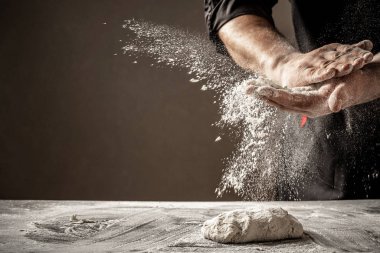 Un ve un serpintili erkek eli fotoğrafı. Ekmek pişiriyorum. Hamuru yoğurmak