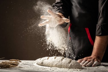 Ekmek pişiriyorum. Hamur ahşap bir mutfak masasında yatıyor ve üzerine un serpiştiriyor.