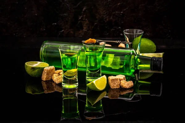 Absinthe eller mynta sprit skott. absint i glas med lime skivor på mörk bakgrund — Stockfoto