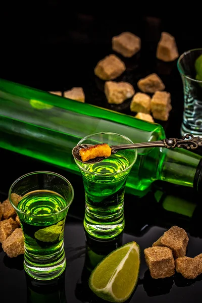 Absinth- oder Minzschnaps. Absinth im Glas mit Limettenscheiben auf dunklem Hintergrund. Alkohol, Luxusspirituosen und gefährliche Schnapsidee mit Kristallglas Absinth — Stockfoto