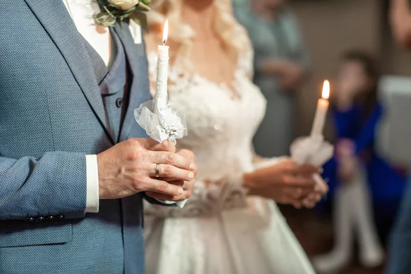 Πνευματικό ζευγάρι, νύφη και γαμπρός κρατώντας κεριά κατά τη διάρκεια της τελετής γάμου στη χριστιανική εκκλησία, συναισθηματική στιγμή κατά τη διάρκεια της τελετής — Φωτογραφία Αρχείου