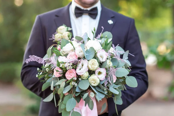 Las flores de boda en las manos del novio. Joven elegante hombre elegante vestido con ropa formal moderna — Foto de Stock