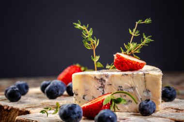 Ahşap masada mavi peynir. Yabanmersini ve çilekle servis edilir. Çevre ürünleri kavramı. Arkaplan resmi. Boşluğu kopyala.