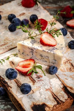 Mavi ve brie peyniri. Ahşap bir arka planda. Yabanmersini ve çilekle servis edilir. Çevre ürünleri kavramı. Arkaplan resmi. Boşluğu kopyala.