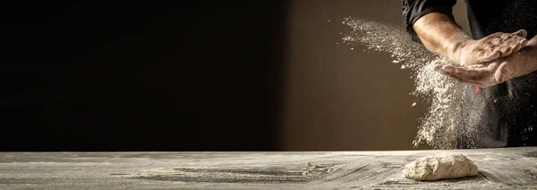 Photo of flour and men hands with flour splash. Cooking bread. Kneading the Dough. Isolated on dark background. Empty space for text.