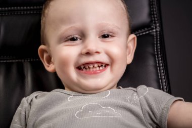 Küçük çocuk diş bakımıyla kamerada gülüyor ve gülüyor. Çocuk büyük gülümsemeyle ön dişlerini gösteriyor..