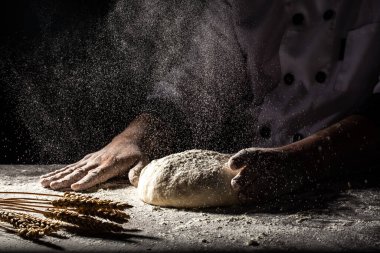 Beyaz takım elbiseli pasta şefi beyaz toz kaplı masaya top hamuru fırlatırken beyaz un havaya uçuyor. Doğa, İtalya, gıda, diyet ve biyoloji kavramı.