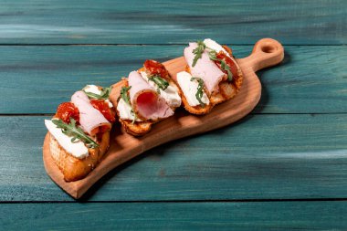 İtalyan antipatik atıştırmalıklarıyla aperatifler. Brie peyniri, roka ve güneşte kurutulmuş domates, jambon. Yemek tarifi geçmişi. Kapat..