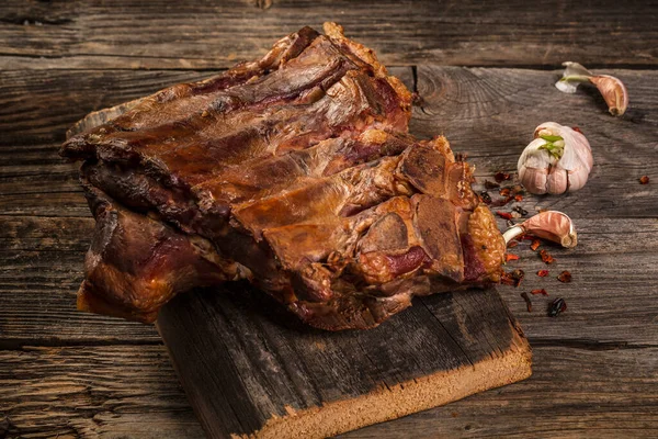 Spicy hot smoked pork ribs. Barbecue meat on an old vintage wooden cutting board.