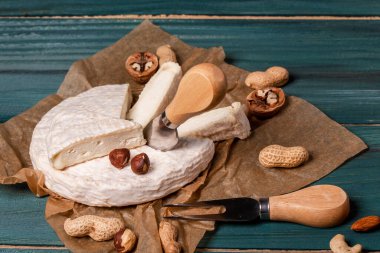 Peynirli peynirli peynirli camembert ve cevizli, kraft kağıdında, ahşap arka planda. Camembert peyniri. Ahşap arka planda peynirli peynirli camembert peyniri. Şarap ve romantizm için yemek.