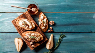 Kahvaltıda kızarmış ekmek, peynirli camembert ve armut, tatlım, ahşap masada ceviz. Üstten metin alanı ile yatay üst görünüm. Düz, tepede. Uzun pankart biçimi.