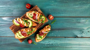 Tost, kızarmış ekmek, ızgara Halloumi peyniri ve bir dilim avokado, kurutulmuş domates, zeytinyağı ve taze aromatik otlar. Lezzetli Akdeniz vejetaryen aperatifi.