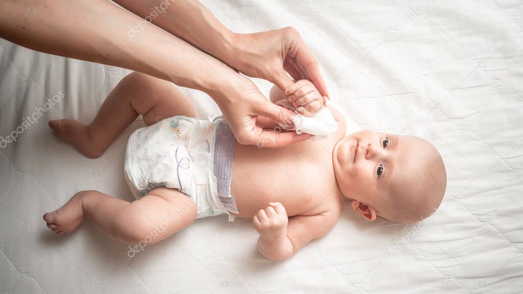 Changing nappies for an adorable little newborn baby. Mother Wiping Baby's Face. Concept Hygiene cleaning wipe, pure, clean.