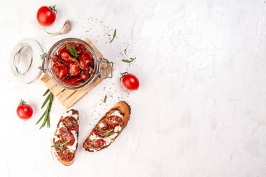 Toast with goat cheese, sun-dried tomatoes and garlic, oregano, olive oil on a light table, top view banner menu recipe place for text. clipart