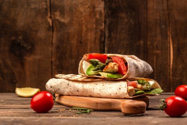 İki taze tavuk kuşkonmaz, ahşap kesme tahtasına avokado tortilla sarılı. Metin için boşluk.