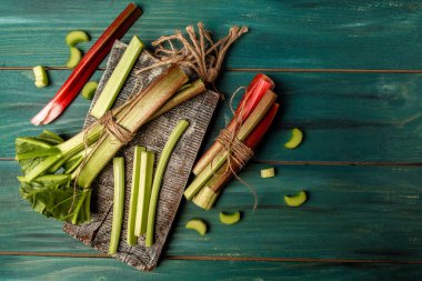 Taze yeşil ve kırmızı rhubarb kırsal bir arka planda saplanır. Yemek tarifi geçmişi. Metin için boşluk. en üstteki görünüm.