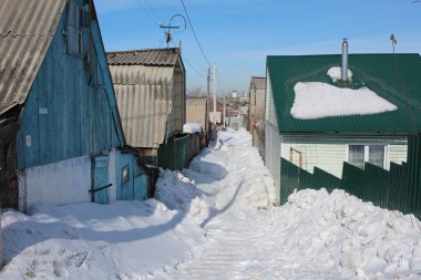 Sibirya 'nın kışın karla kaplı köyünde ahşap evler arasında tedavi edilmemiş dar bir geçit.