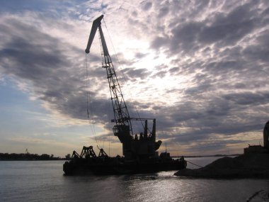 Nehir limanında kum madenciliğinde yüksek kargo vinci.