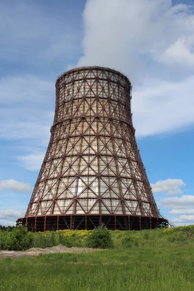 a large pipe a cooling tower at a thermal power plant for the production of heating an engineering construction of a CHP plant in a closed area behind a fence lattice