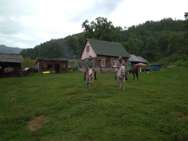 Rusya, Gorny Altai 05.08.2019: Altai Dağı 'nın taygasında at sırtında seyahat eden koruyucu kıyafetli insanlar