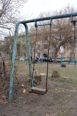 Rusya, Novosibirsk 05.05.2019: Sonbaharda çok katlı bir binanın bahçesinde eski paslı salıncak