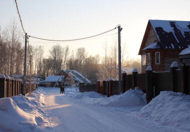 Rusya, Novosibirsk, 01.01.2019: köy sakinleri kışın yol boyunca evlerin yakınındaki bahçelerde yürürler.