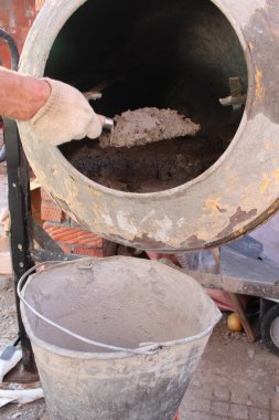 İnşaat işçisi, inşaat alanındaki bir kovaya beton karıştırıcıdan çimento ve beton harç koyar.