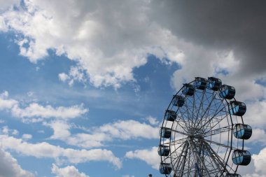 Eğlence parkında gökyüzüne karşı büyük bir dönme dolaba binmek.