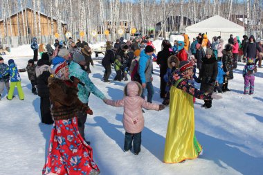 Rusya, Novosibirsk, 09.03.2019: Büyük bir insan ve çocuk kalabalığı kışın Sibirya 'da ormanda eğleniyor, kadınlar oynamaktan mutlu.