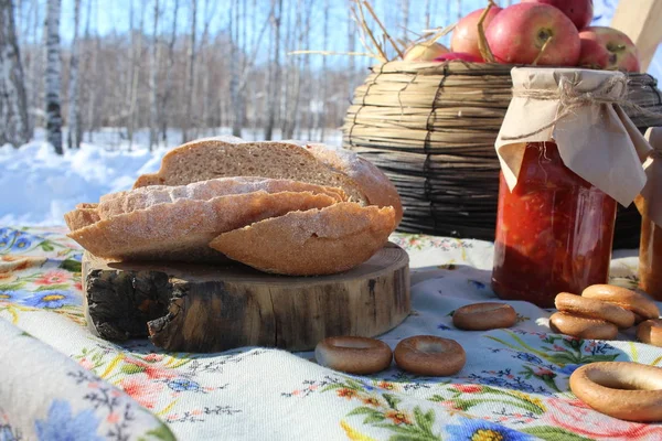 treats on the table bread and apples in jars on a holiday in Siberia in the winter in the forest