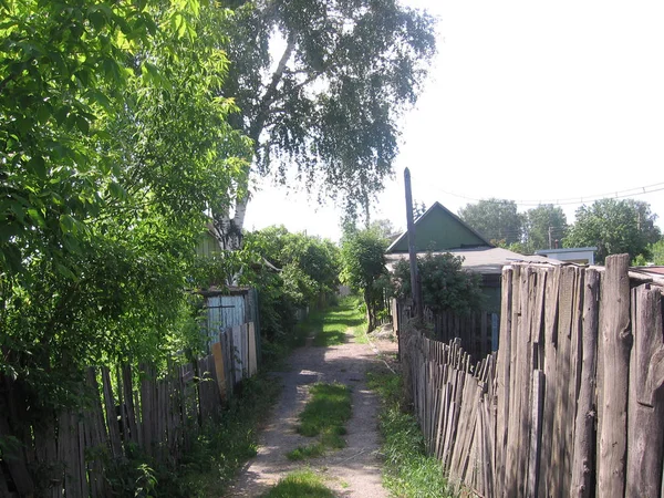 Enger Durchgang zwischen Häusern in der Nähe von Zäunen im Dorf im Sommer — Stockfoto